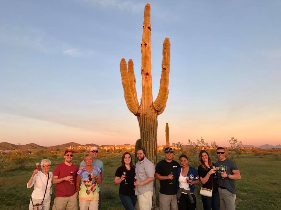 people posing in front of a saguaro cactus